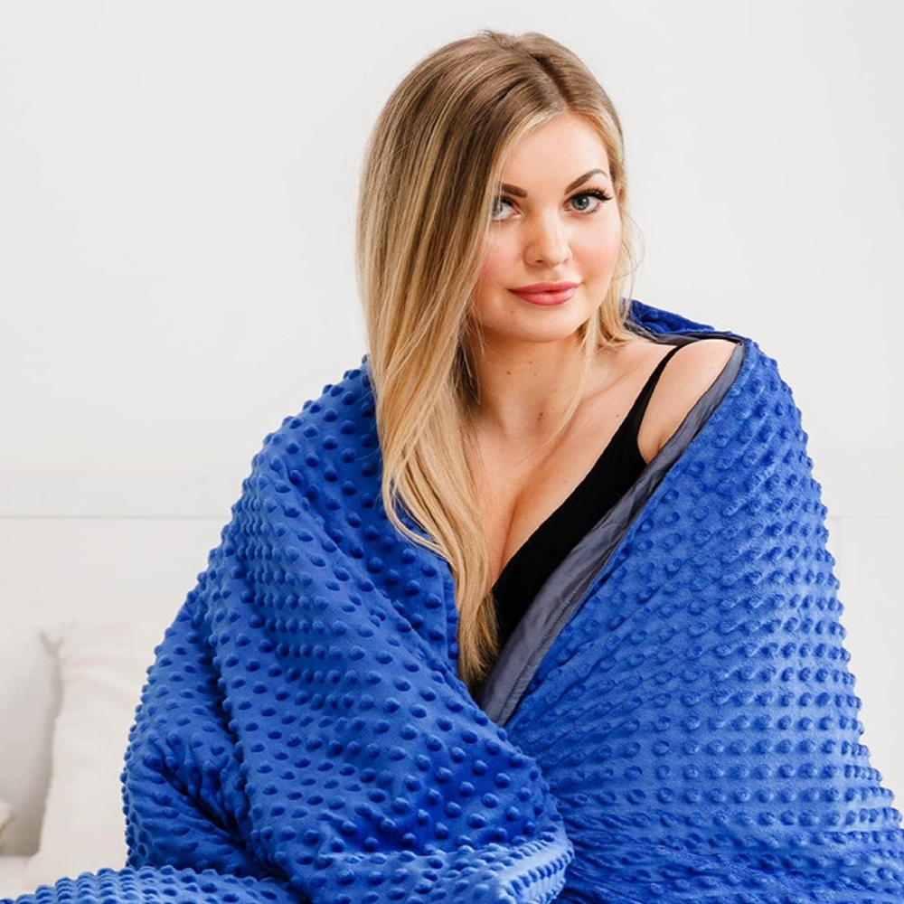 Woman wrapped in a cozy blue weighted blanket.